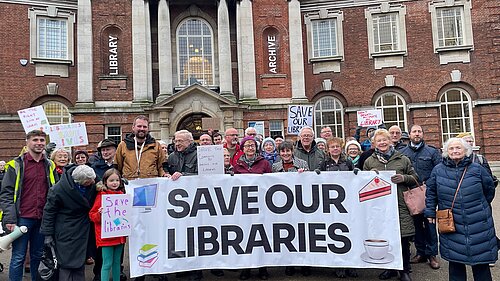 Picture of Lib Dem campaigners staging a protest in front of the Central York Library, holding a banner emblazoned with Save Our Libraries