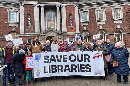 Picture of Lib Dem campaigners staging a protest in front of the Central York Library, holding a banner emblazoned with Save Our Libraries