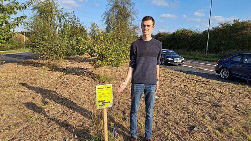 Lib Dem Campaigner Caleb Pell by the ‘Buzz about York’ sign with litter all around