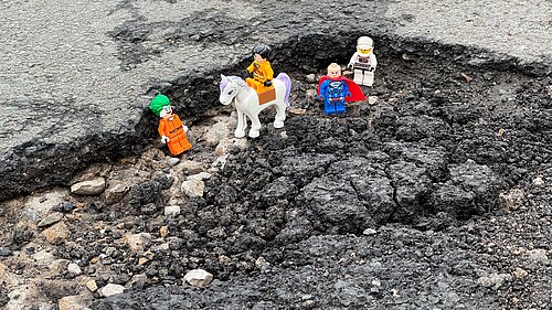Lego figures placed inside a pothole