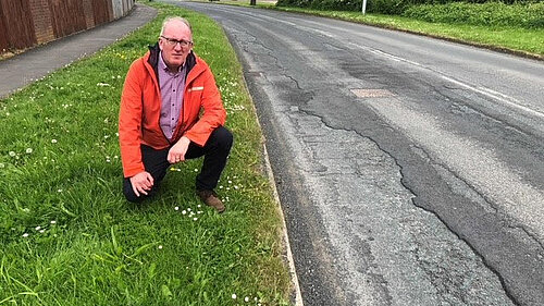 Councillor Fenton by a large pothole