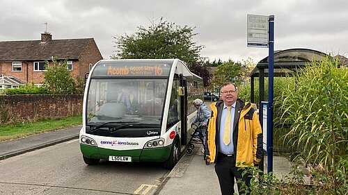 Cllr Andrew Waller standing in front of a Number 16 bus