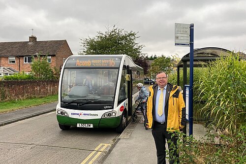 Cllr Andrew Waller standing in front of a Number 16 bus