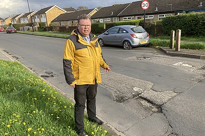 Cllr Waller pointing at a pothole on Foxwood Lane