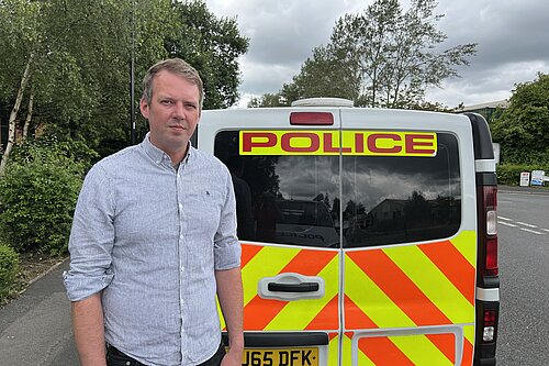 Andrew Hollyer standing by a police van