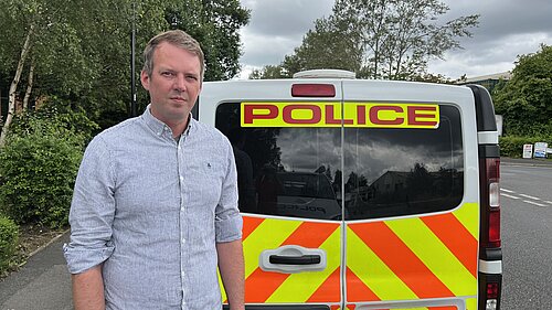 Andrew Hollyer standing by a police van