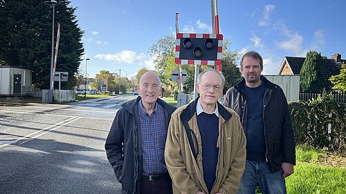 Ian Cuthberton, Richard Watson, and Andrew Hollyer standing by a level crossing in Haxby